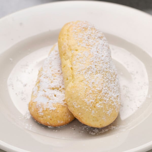 2 gluten free ladyfingers with powdered sugar on white plate