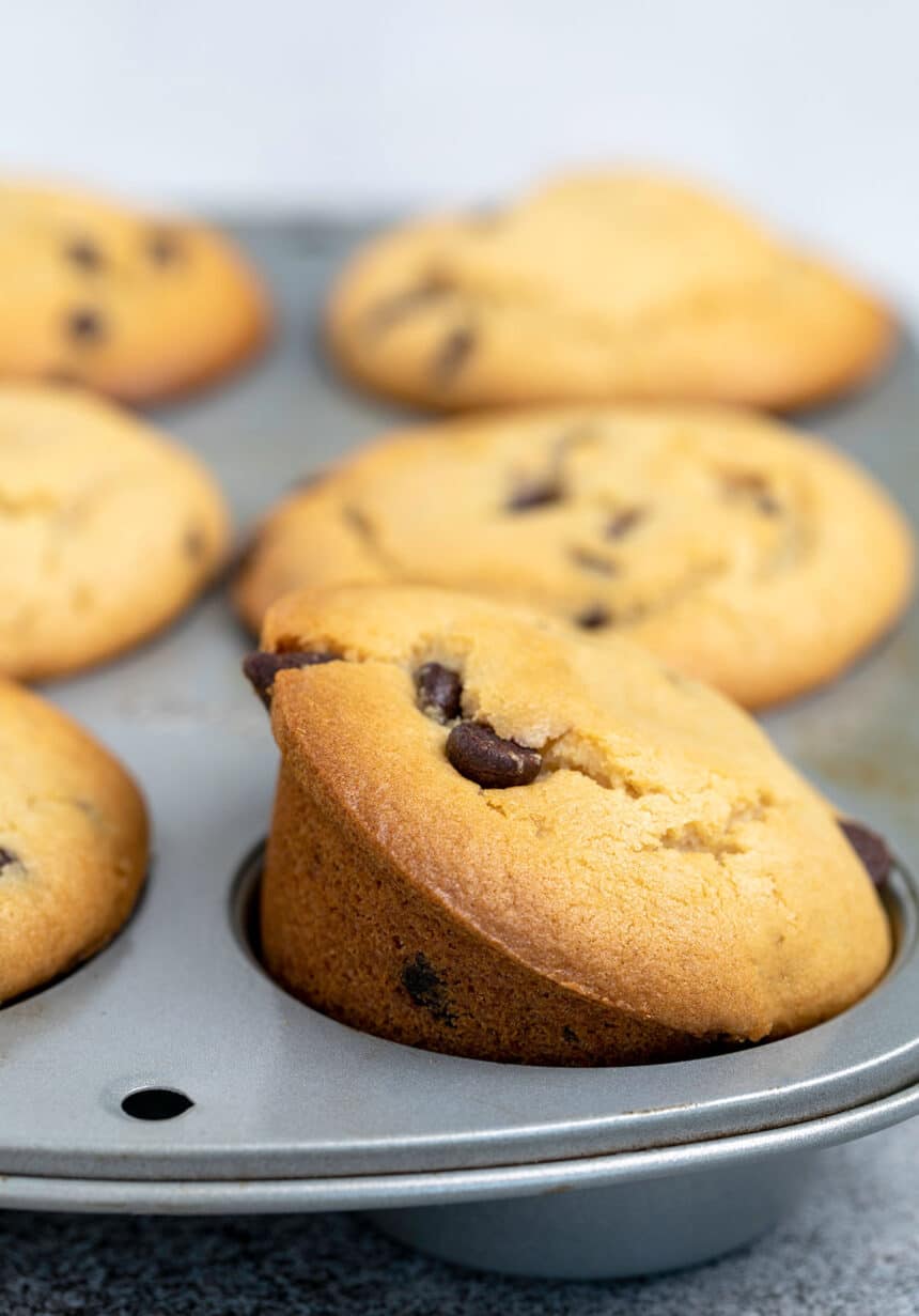 6 chocolate chip muffins baked in muffin tin with one on its side