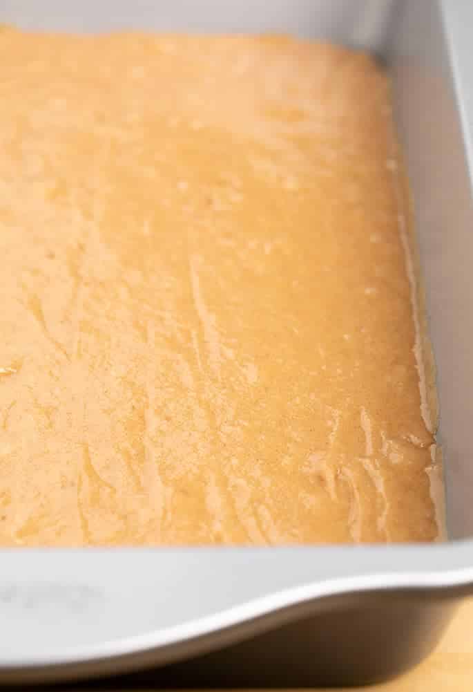 Raw light brown cake batter in 9x13 inch cake pan