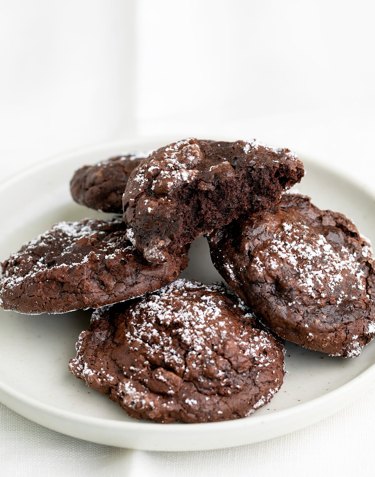 5 chocolate cookies on a small white plate one with a bite taken