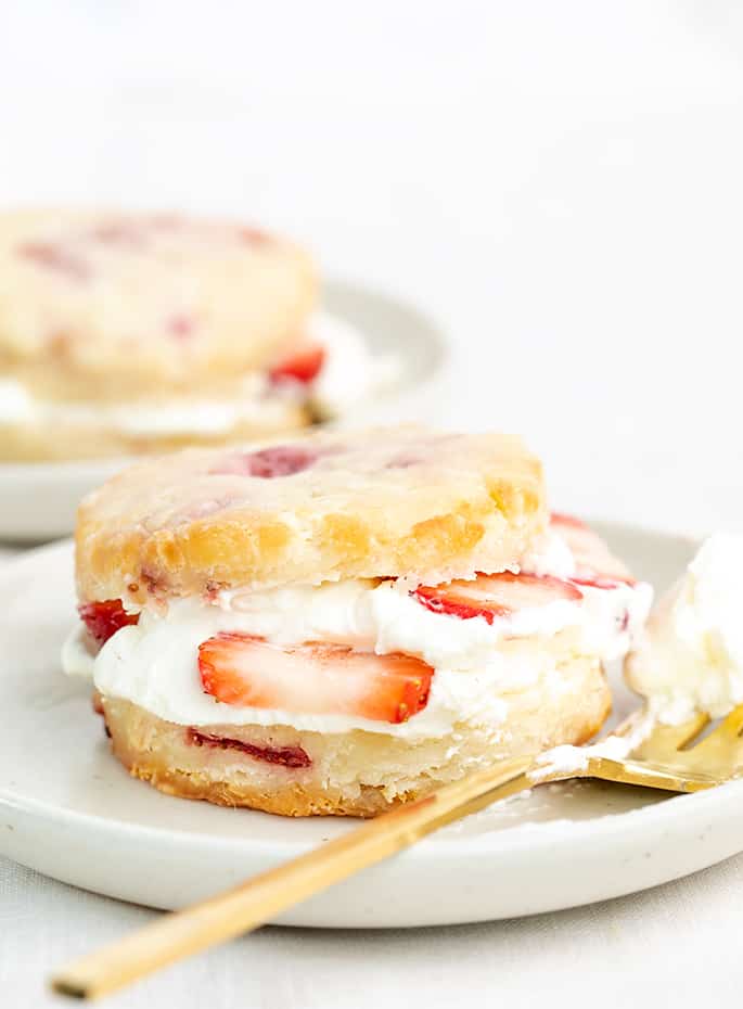 Two strawberry shortcake biscuits with whipped cream and sliced strawberries in the center