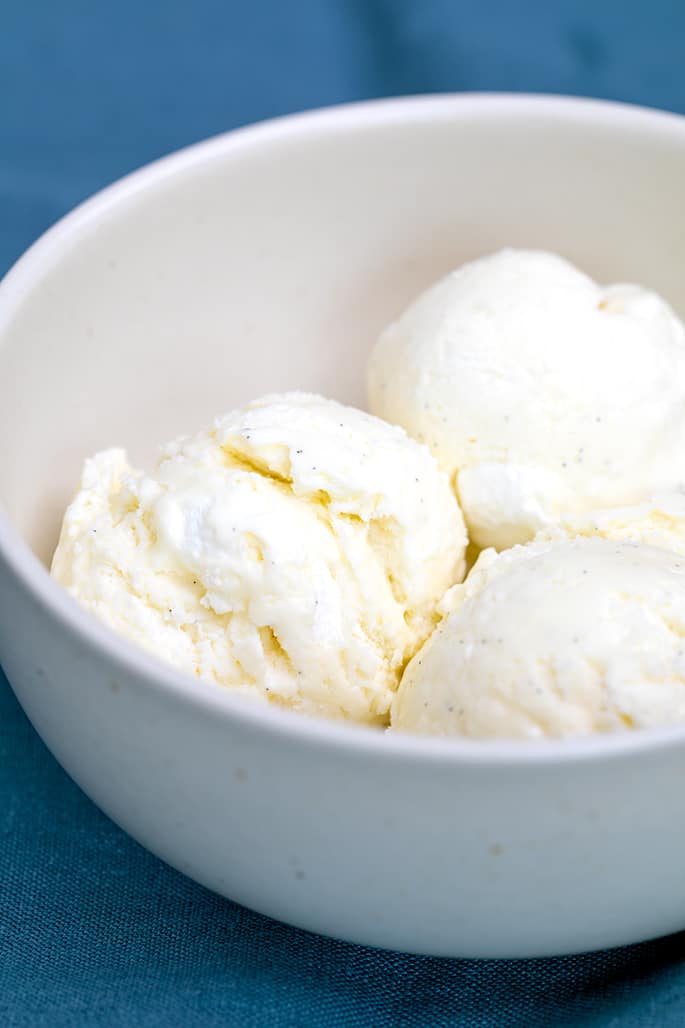 3 scoops of marshmallow ice cream in small white bowl on blue cloth