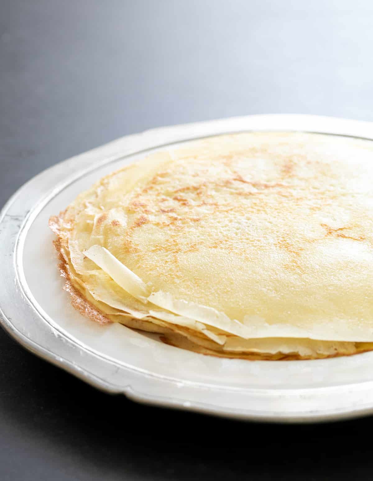 Gluten free crepes in stack on white plate with black border