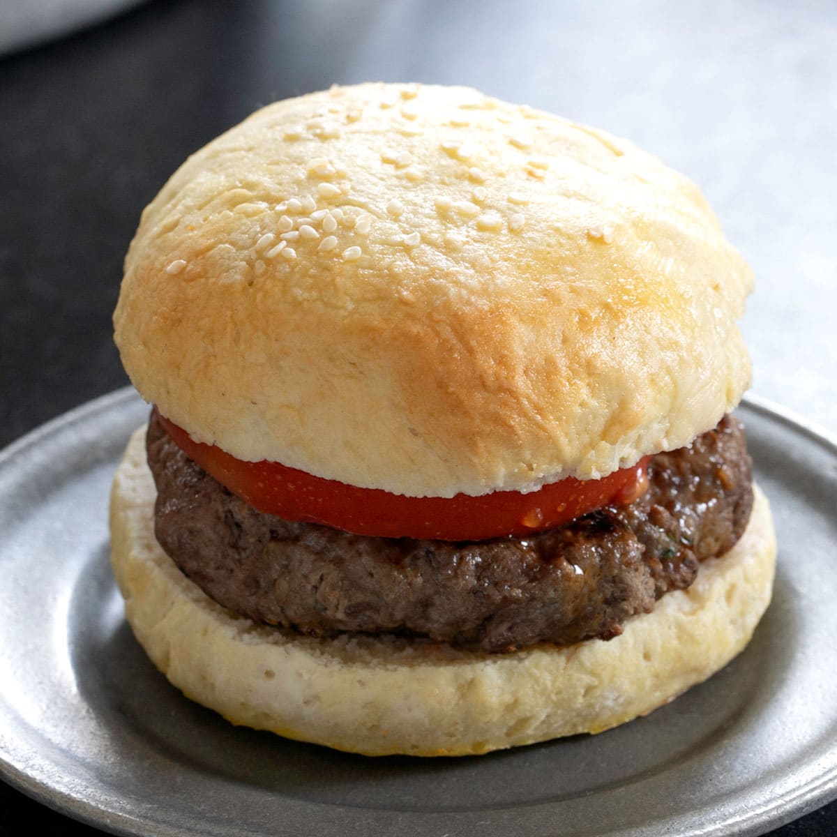 gluten free buns with a hamburger and tomato on small plate