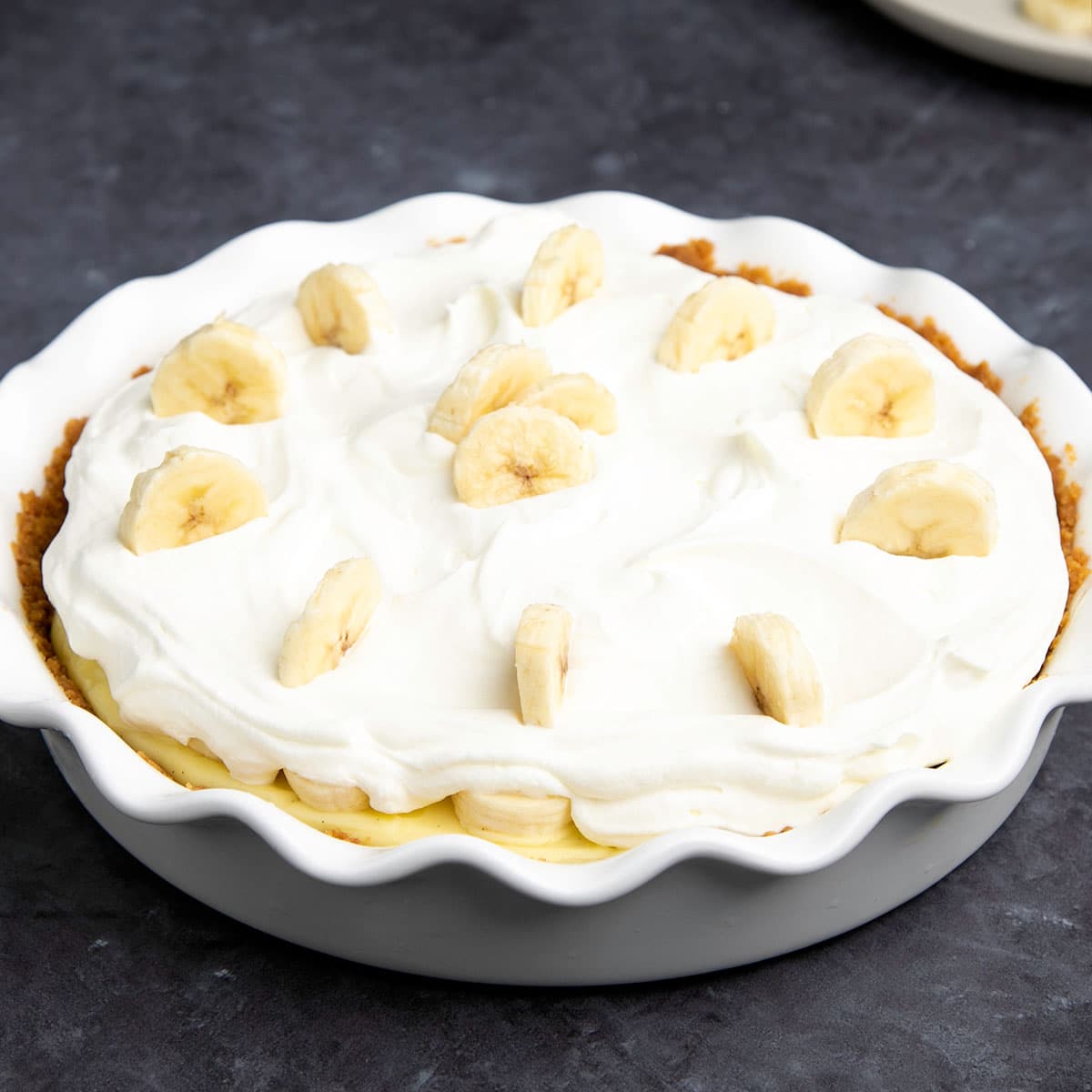 whole gluten free banana cream pie with banana slices on top of cream topping