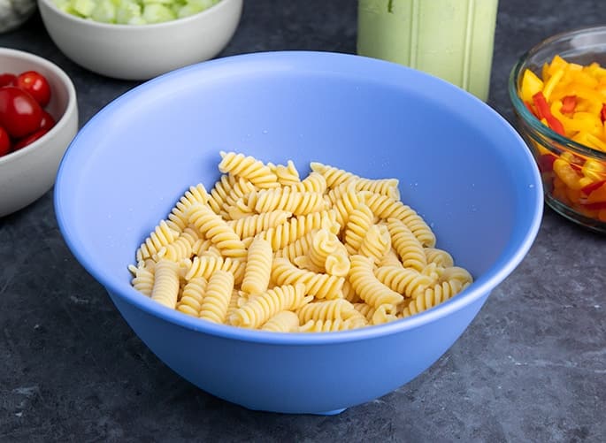 Cooked fusilli pasta in blue serving bowl