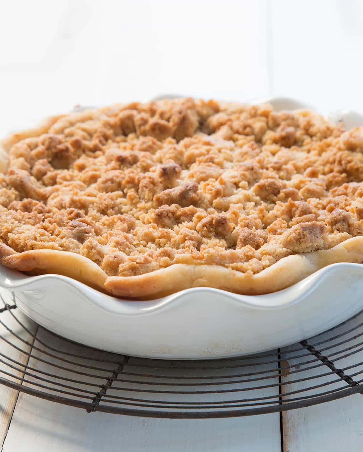 Freshly baked pie in a white ceramic pie dish, with a golden crust and crisp, browned topping.