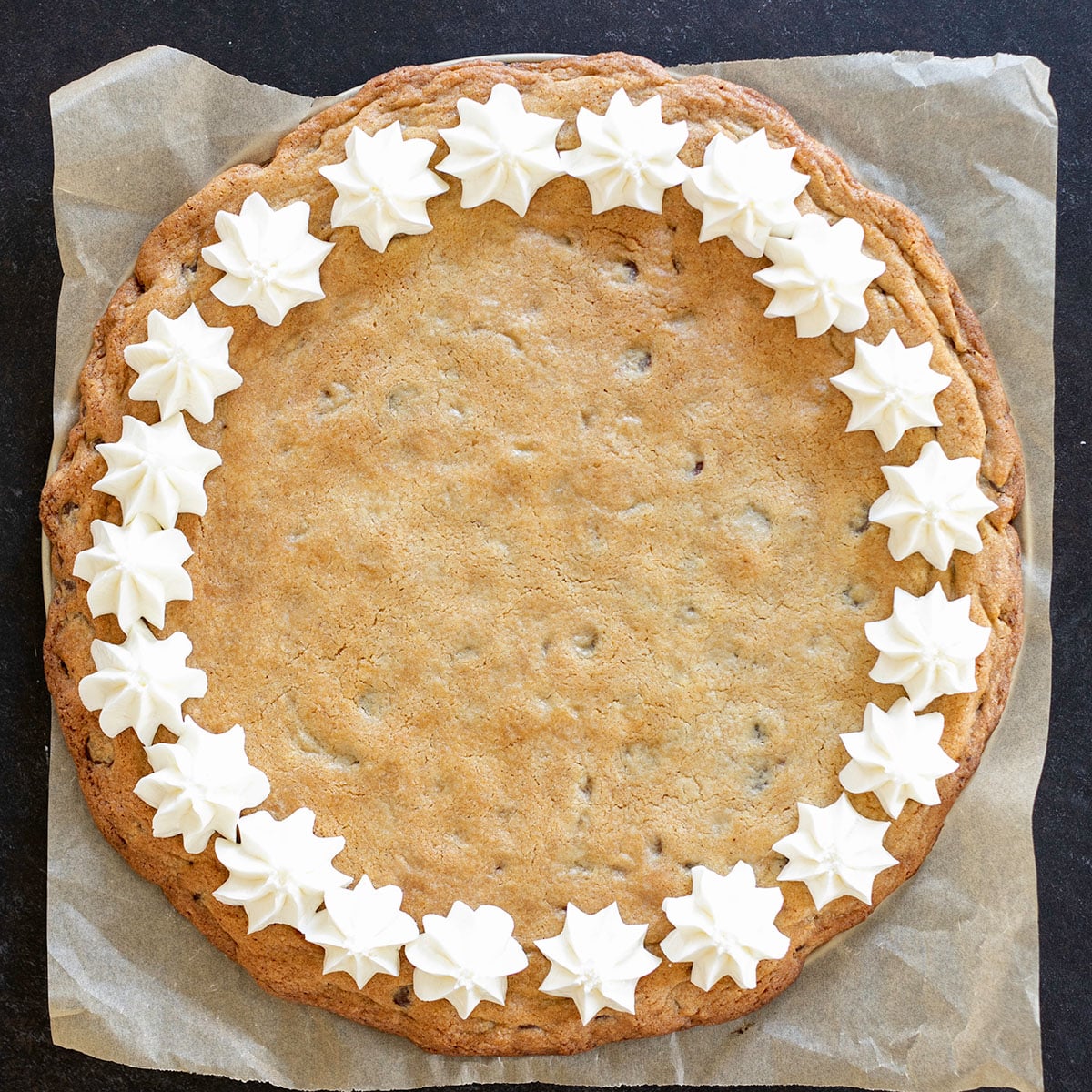 overhead image of gluten free cookie cake with border of star shaped white frosting