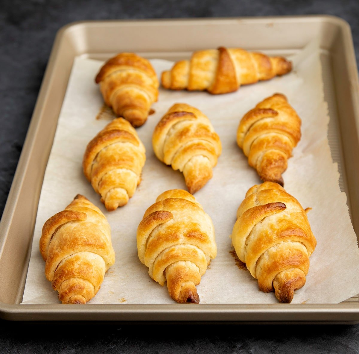 8 baked gluten free croissants on white paper on tray