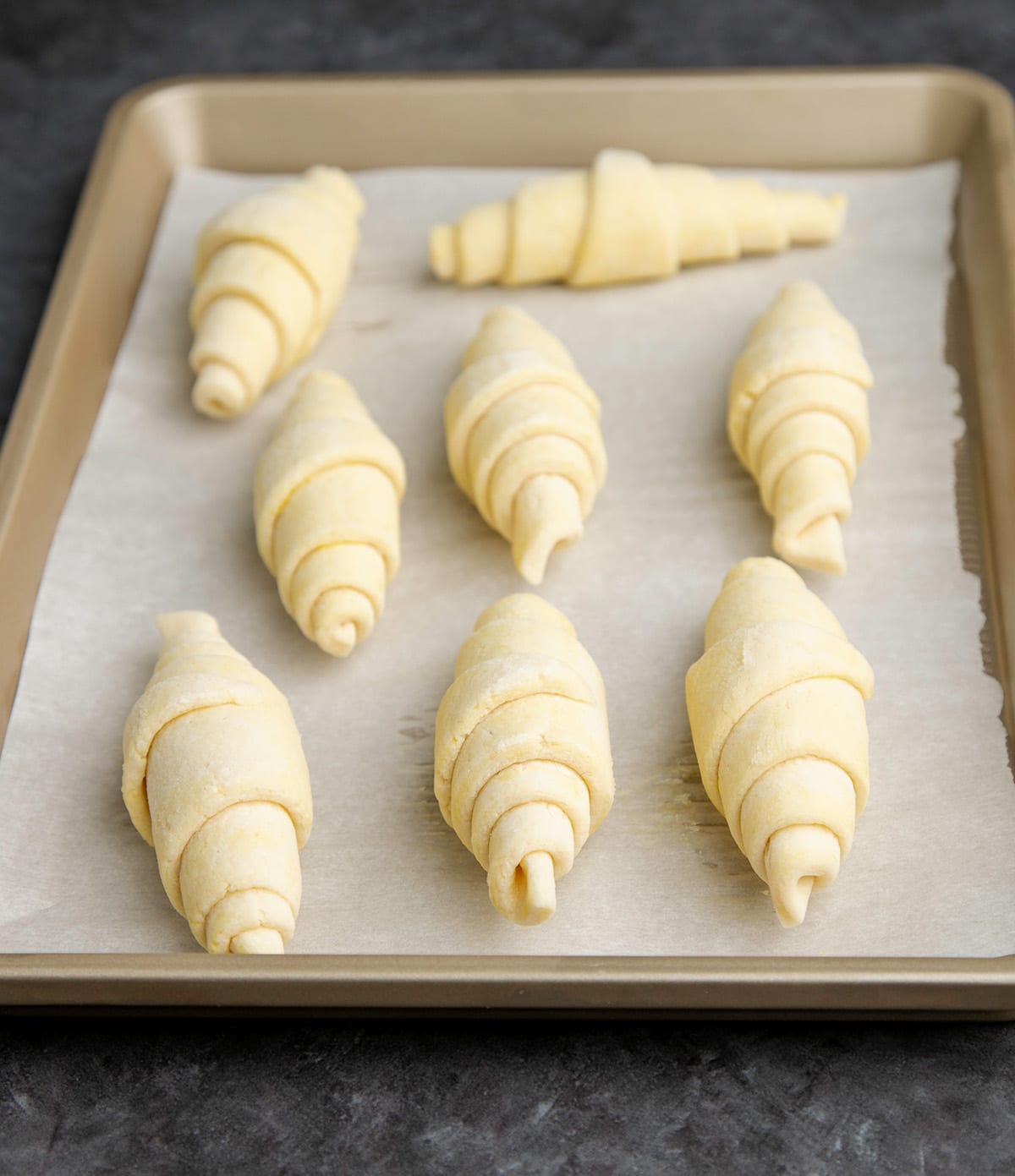 8 raw gluten free croissants on white paper on baking tray