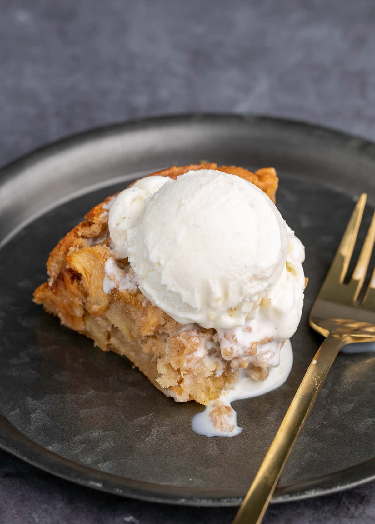 Closeup image of gluten free apple cake with ice cream and bite taken with fork