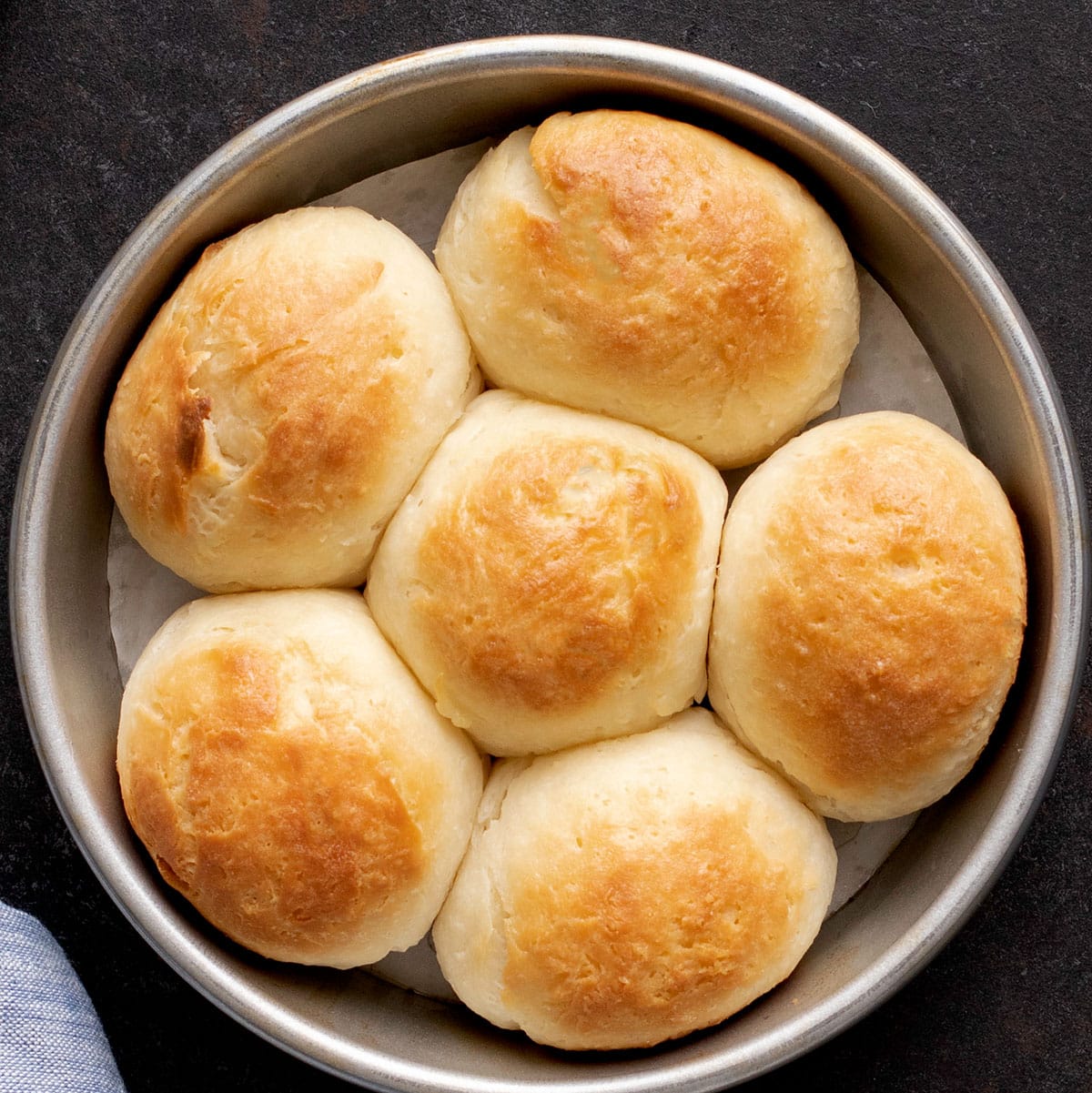 6 light brown soft gluten free dinner rolls in round baking dish