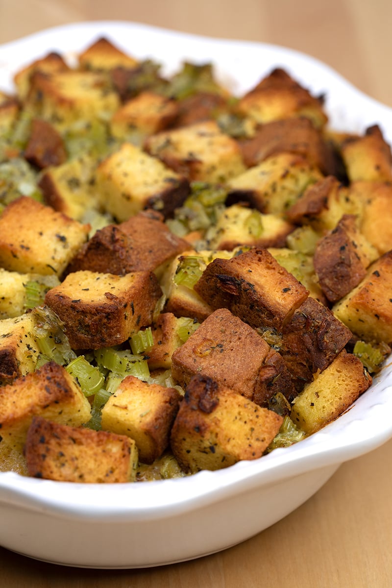 Baked gluten free stuffing in white casserole dish on wood table