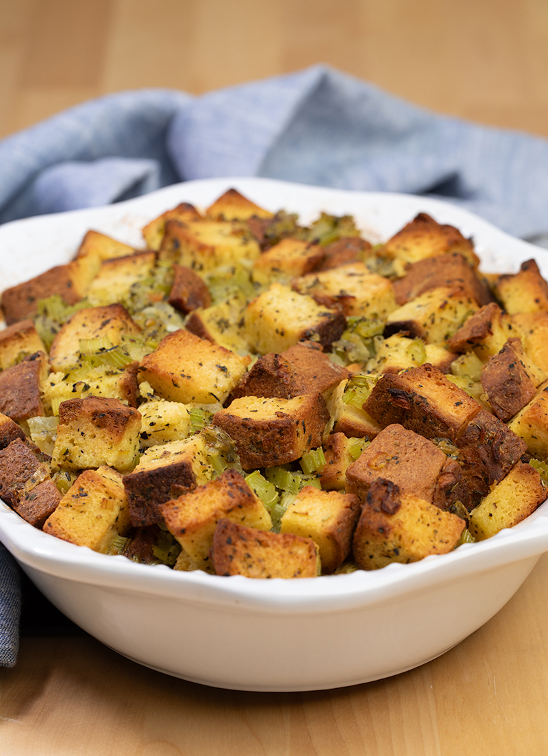 Baked gluten free stuffing in white casserole dish with blue cloth