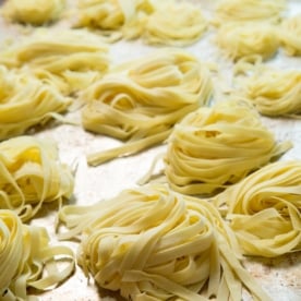 nests of raw gluten free pasta on metal baking sheet