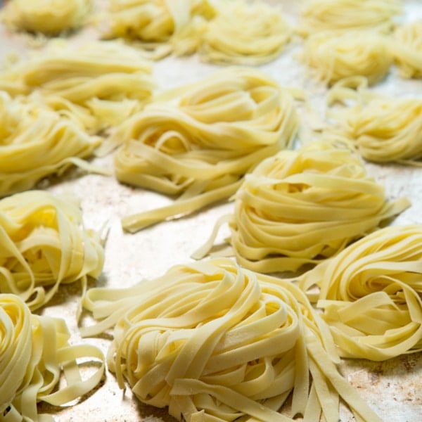 nests of raw gluten free pasta on metal baking sheet