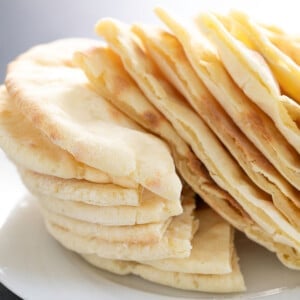 8 gluten free pita bread cut in half and stacked on white plate