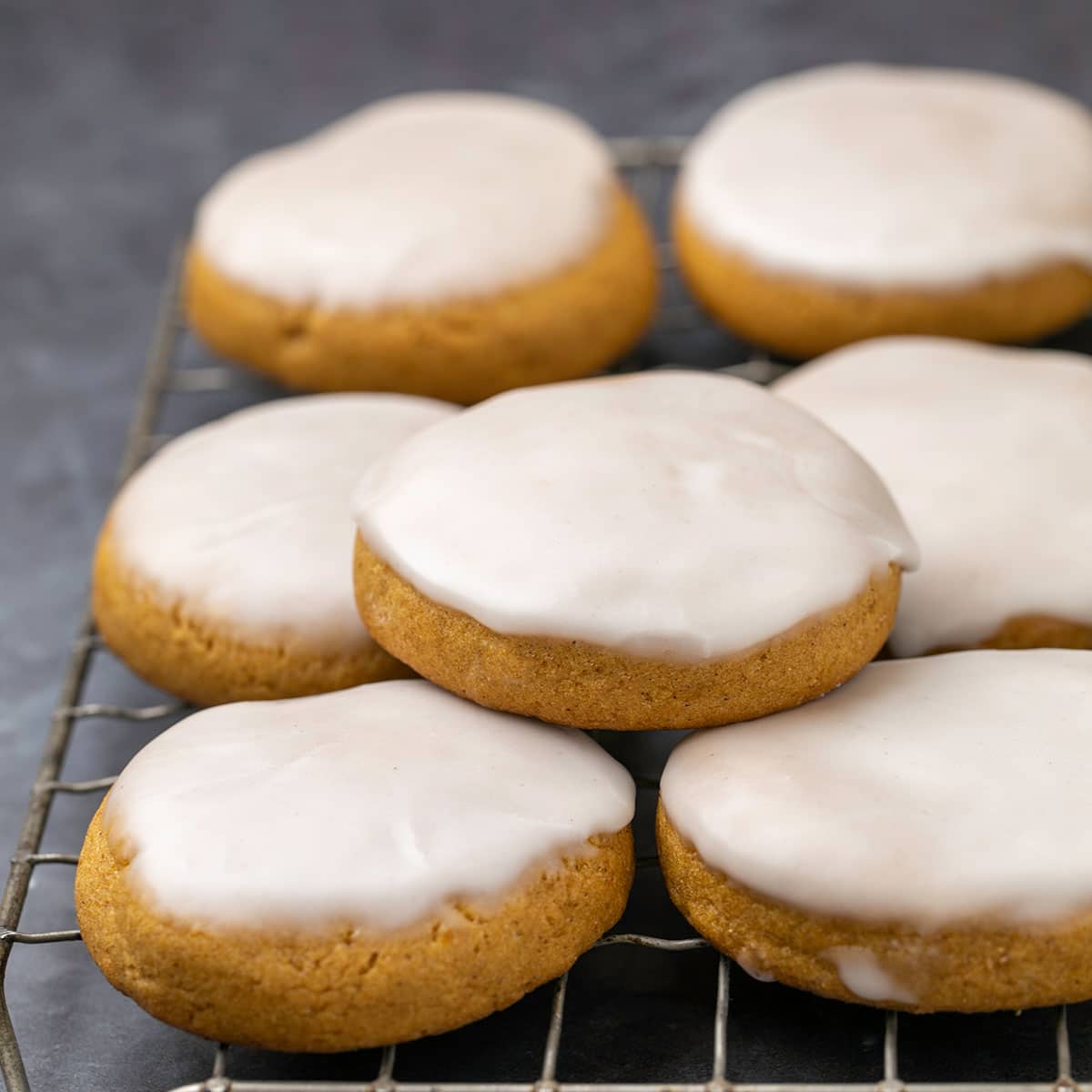 7 gluten free pumpkin cookies with white icing on wire rack