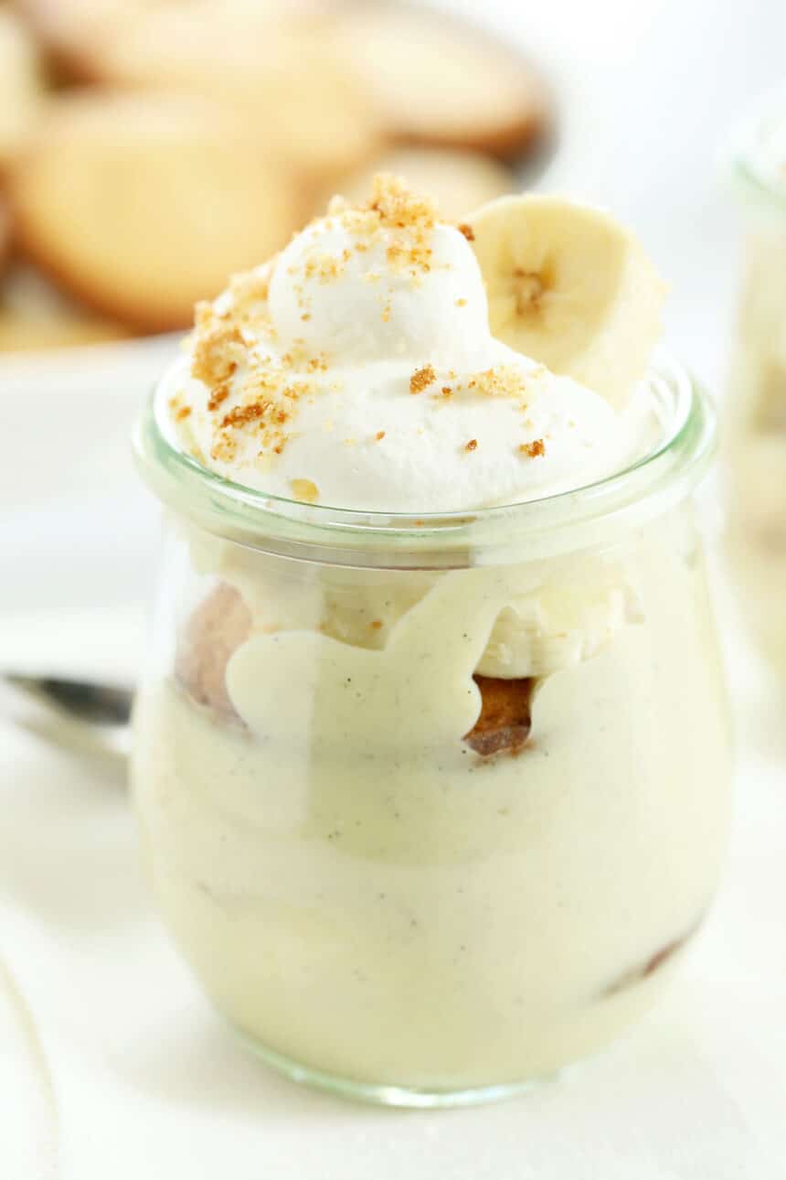 Banana pudding in a small jar with whipped cream and banana