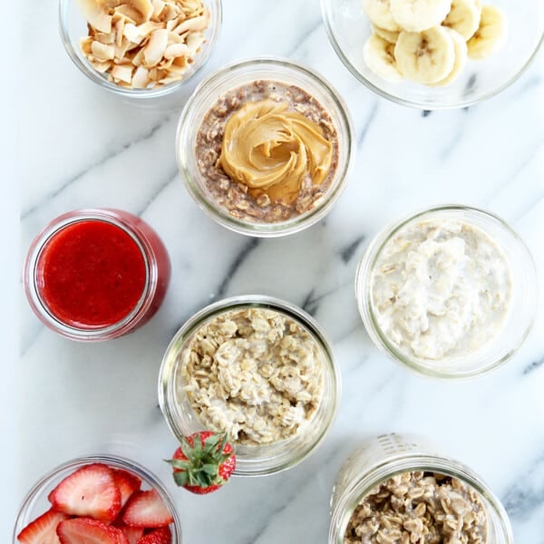 overhead image of gluten free overnight oats varieties in glass jars with toppings