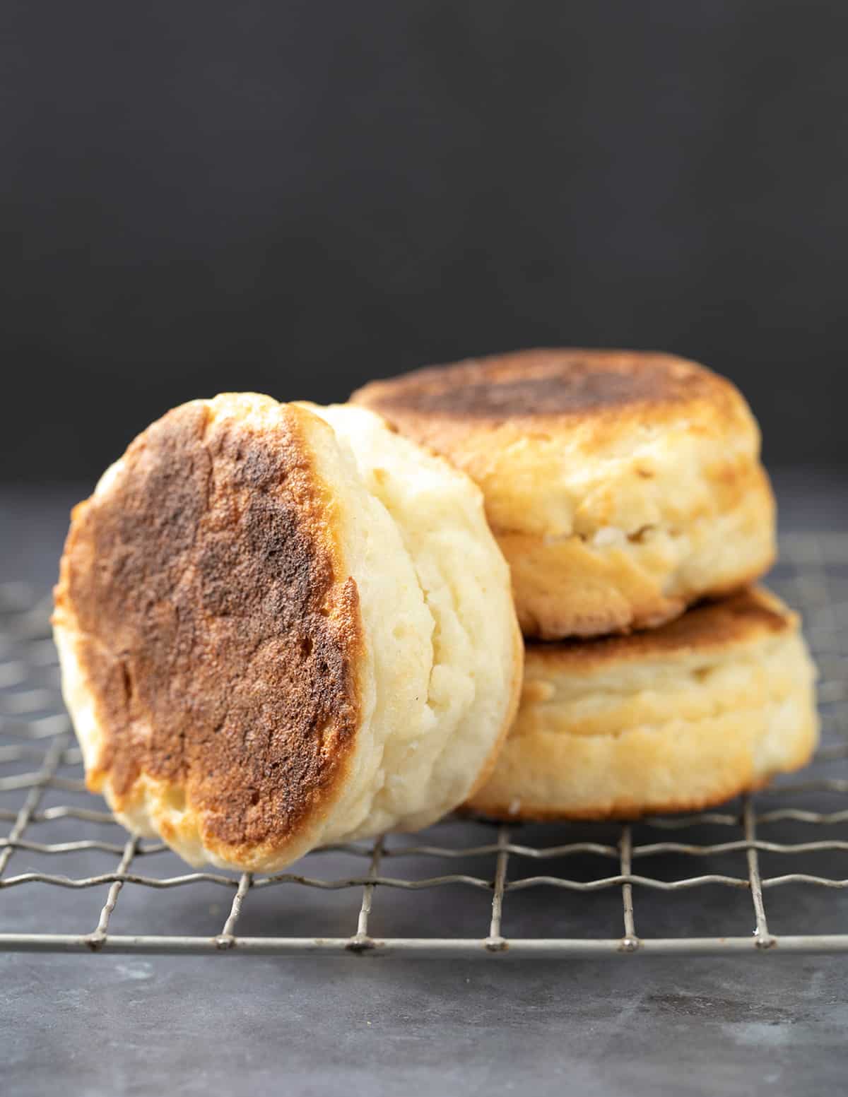 Stack of 2 English muffins with one more on its side all on a wire rack