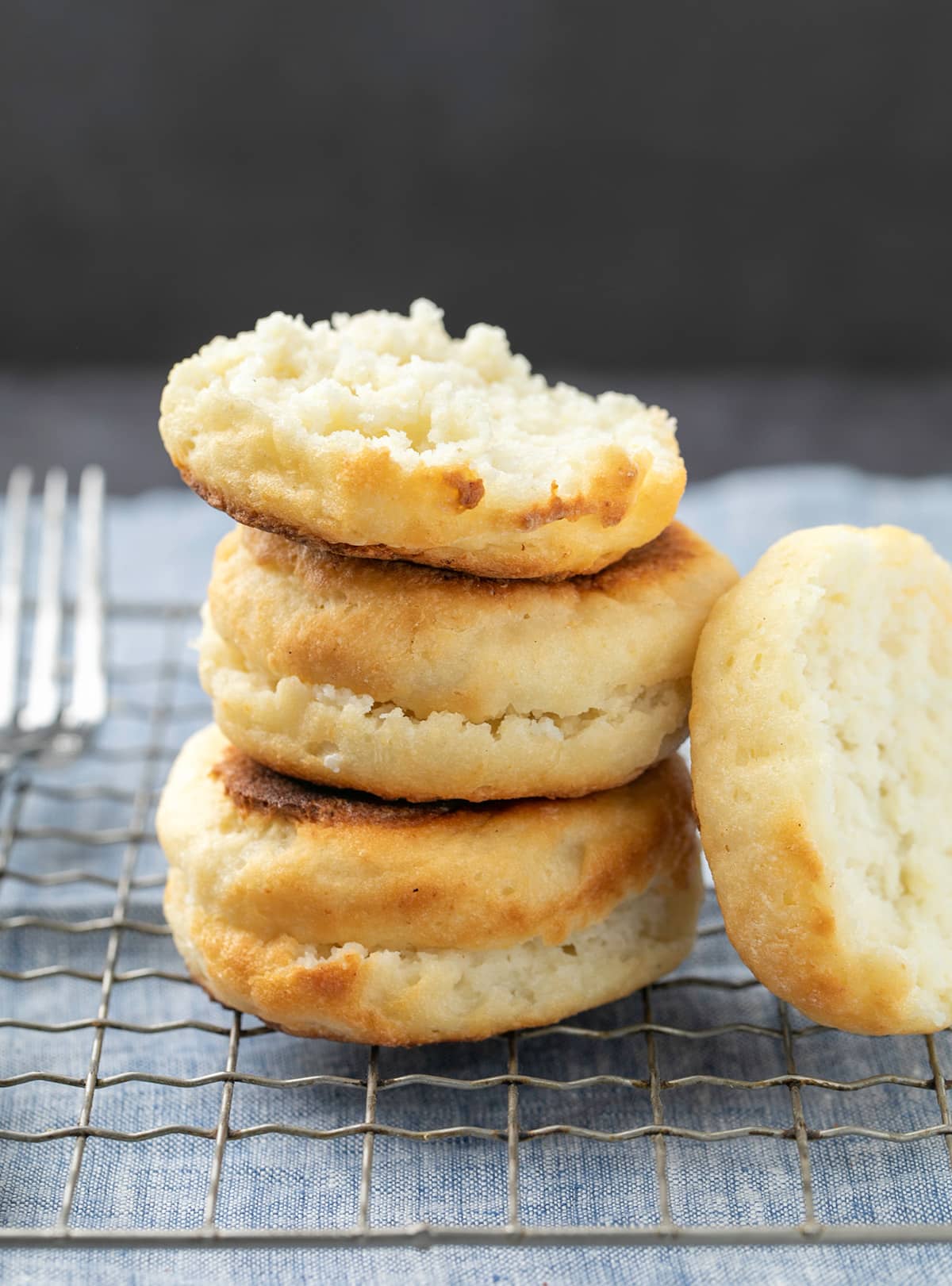 Stack of 2 full and one half English muffins with half propped on side on wire rack with fork