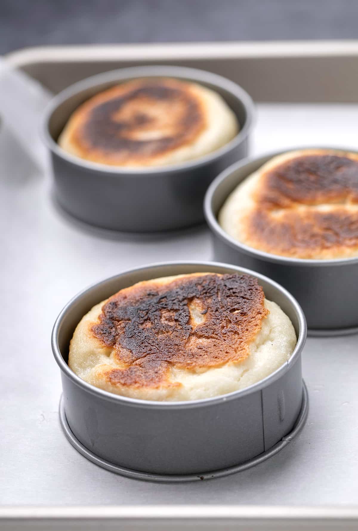 Three English muffins in rings on white paper on a tray
