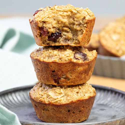 stack of 3 baked oatmeal cups on gray plate, top with bite taken