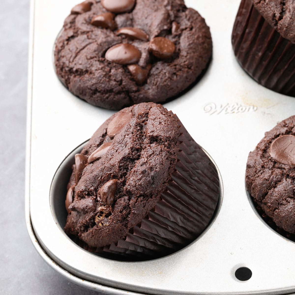 gluten free chocolate muffins in metal muffin tin with one muffin on its side