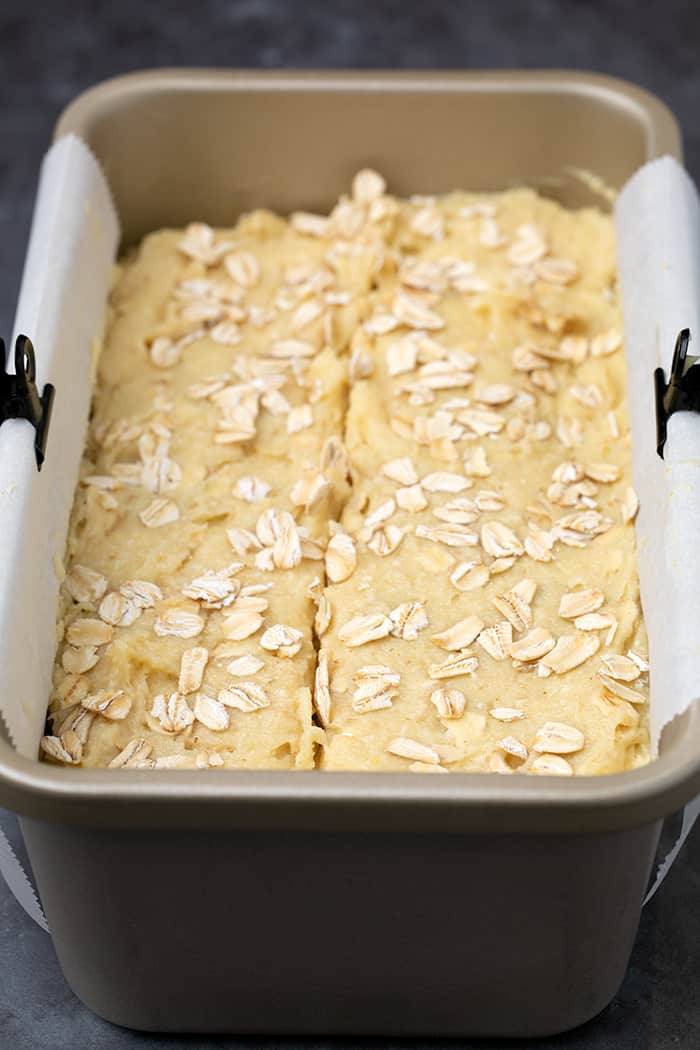 Oat bread batter in loaf pan on white paper with clips