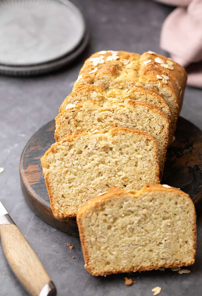 https://glutenfreeonashoestring.com/wp-content/uploads/2023/01/Sliced-oat-bread-on-wround-wood-with-plates-and-purple-cloth-in-background.jpg