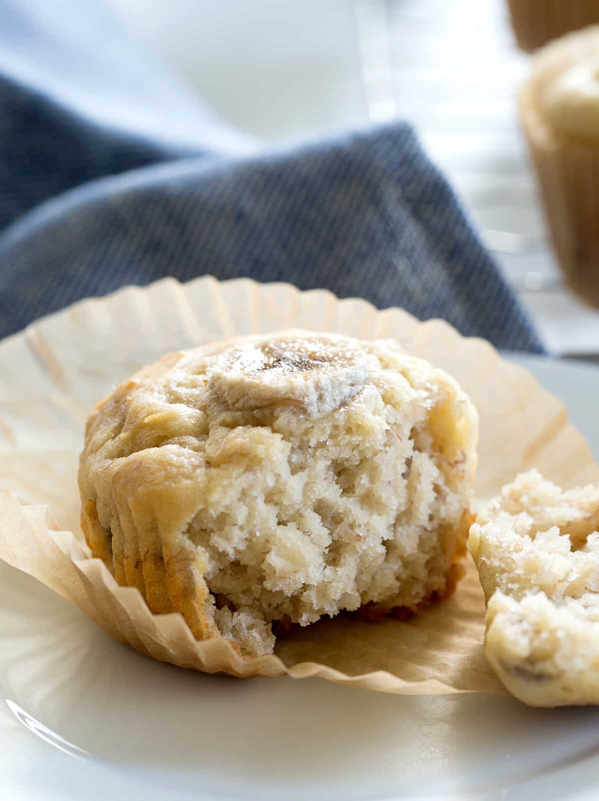 A muffin sitting in peeled liner with front of muffin removed and moist crumbs attached.