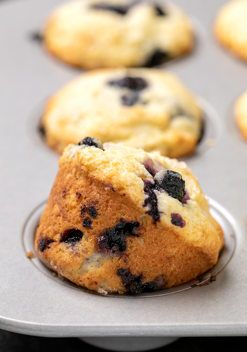 gluten free blueberry muffin on its side in a metal muffin tin