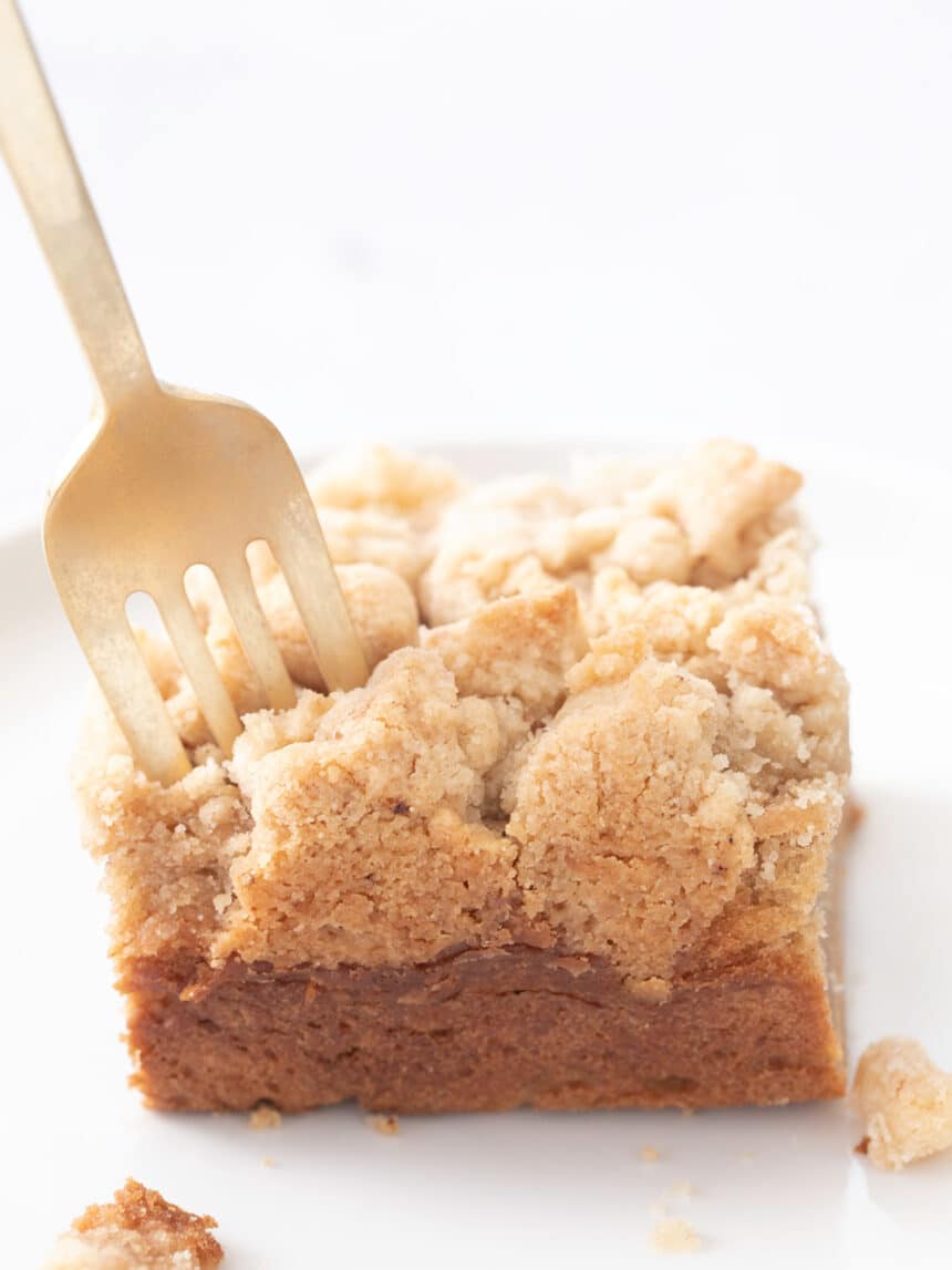 Fork stuck in square of gluten free coffee cake on a white plate
