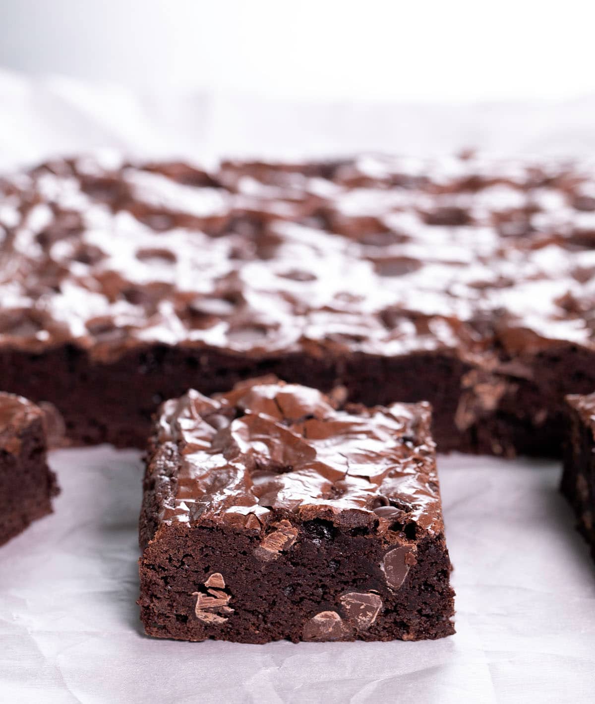 Gluten free brownies cut in squares on white crinkled paper.