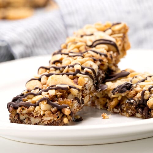 2 homemade cereal bars with chocolate drizzle on white plate