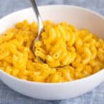 gluten free mac and cheese in white bowl with metal spoon