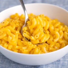 gluten free mac and cheese in white bowl with metal spoon