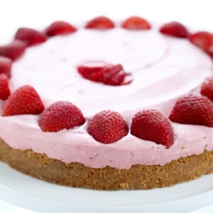 whole uncut strawberry cheesecake with graham cracker crust and strawberry halves along perimeter and in center