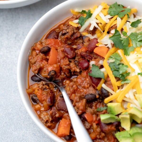 gluten free chili in bowl with spoon and toppings