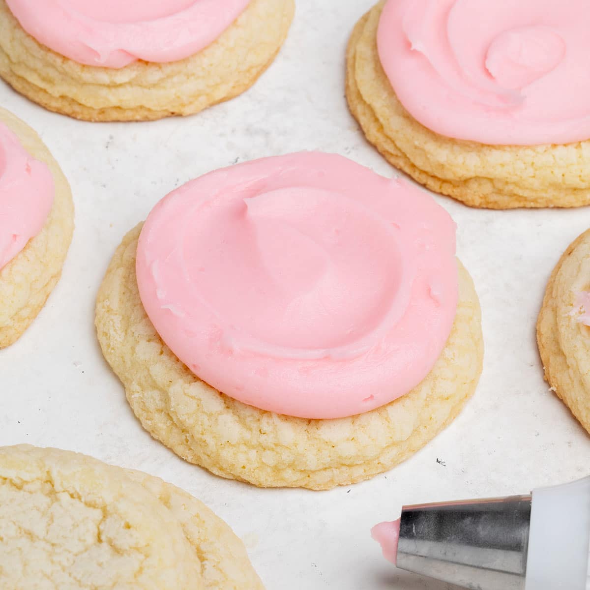 gluten free crumbl cookies sugar cookies with pink icing on white surface