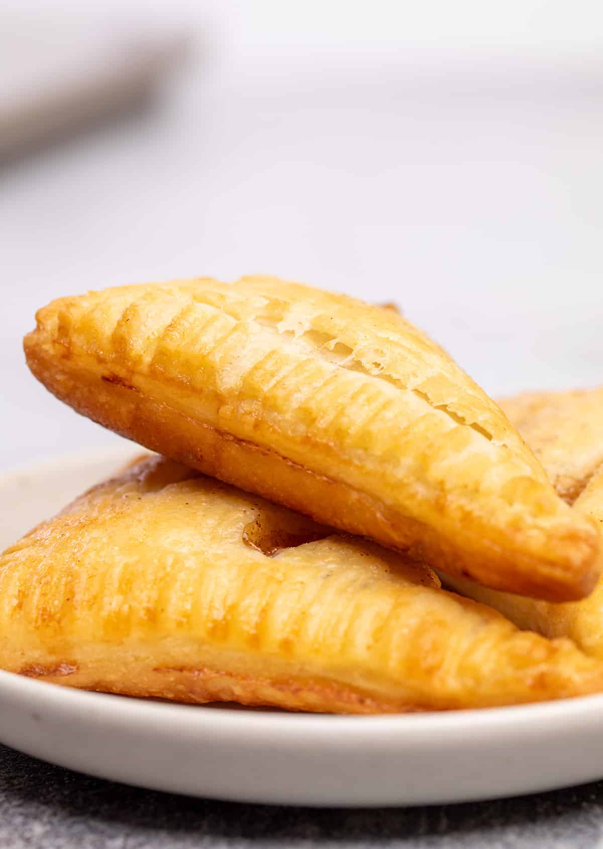Light brown triangle gluten free puff pastry on small white plate.
