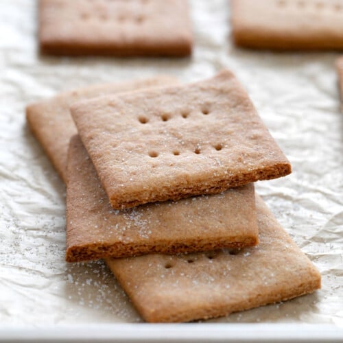 small stack of gluten free graham crackers with one broken in half on brown paper