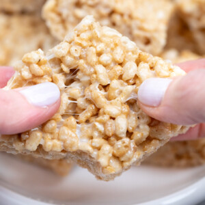 Fingers pulling apart square rice krispie treat