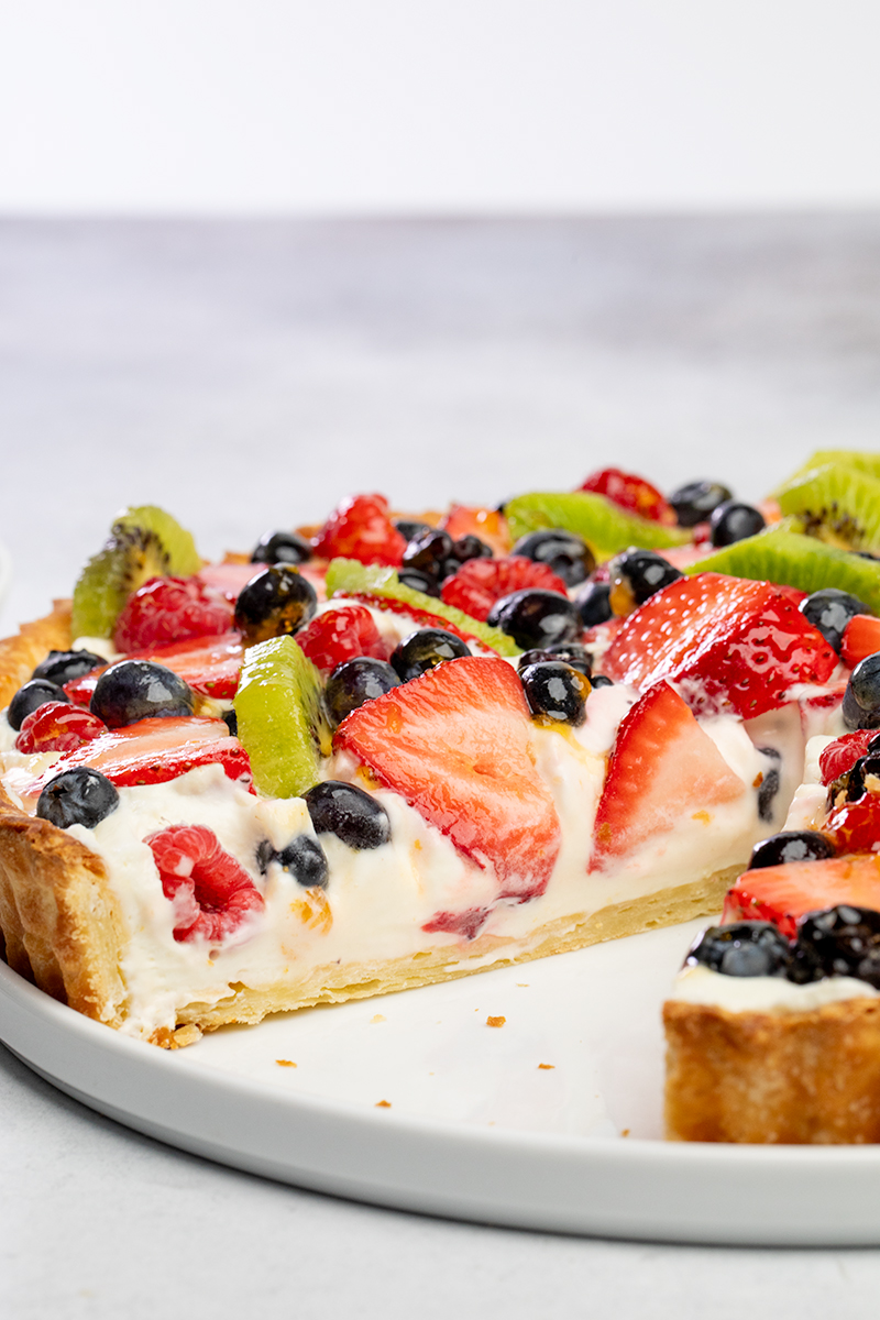 Inside of fruit tart on round white platter with slice removed