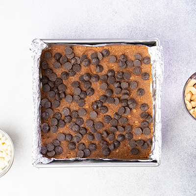 7 layer bar crust in pan with semi sweet chocolate chips on top