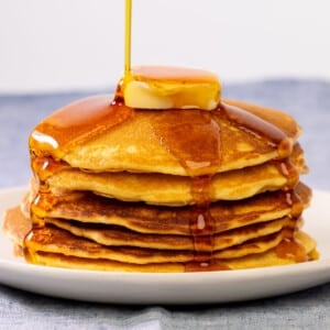 cornmeal pancakes in stack with syrup and butter