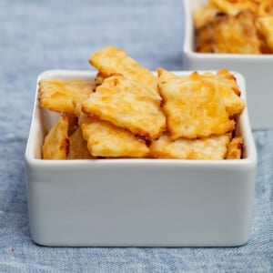 pile of square yellow cheese crackers in square white bowl