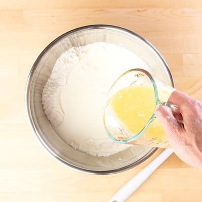 Sheet pan pancake batter pouring in melted butter and eggs