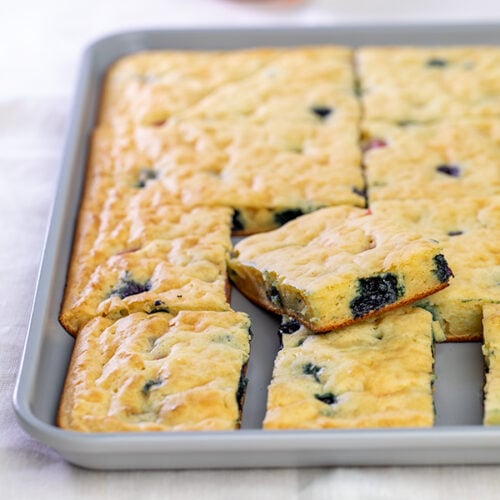 gray baking sheet pan with light brown squares of pancakes with blueberries